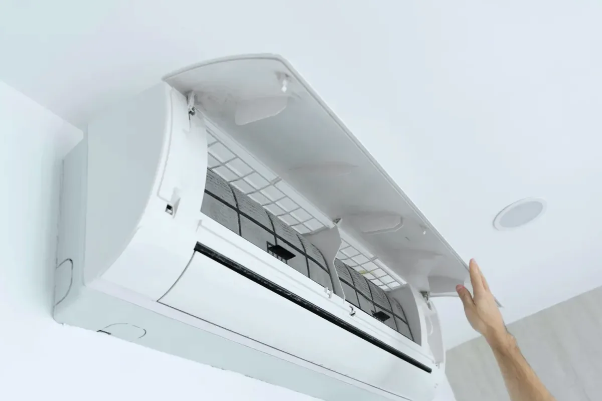 Hand opening the cover of a wall-mounted ductless air conditioner